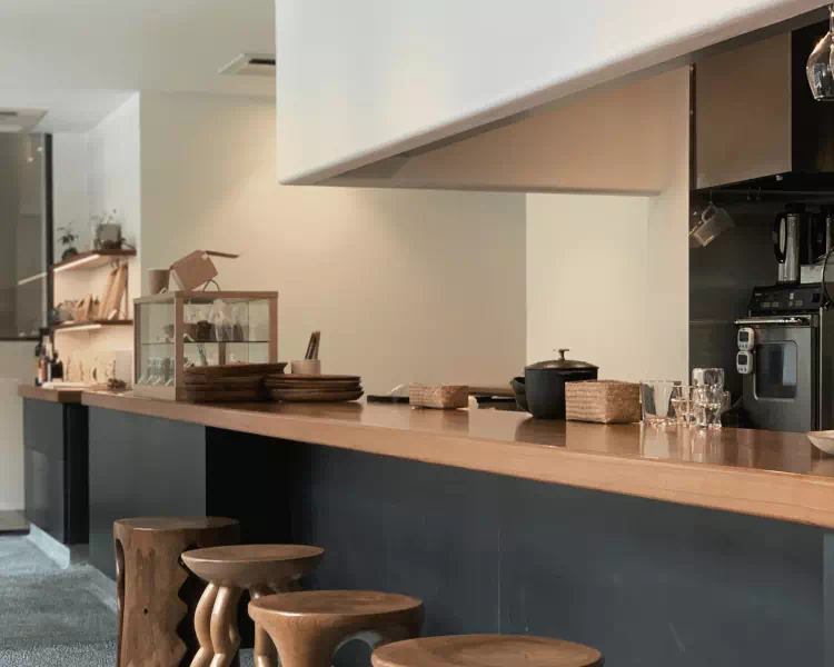 Une cuisine noire et en bois avec un mur beige