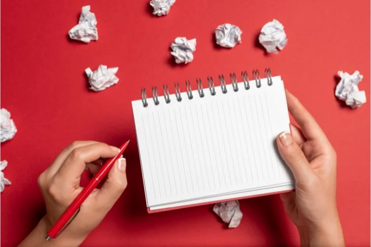 Une personne qui écrit un brouillon sur un carnet