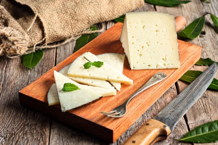 Une planche de manchego découpée avec des feuilles de menthe.