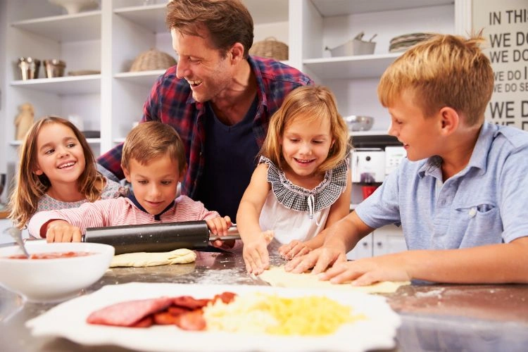 Père et ses enfants en train de faire une pizza en s'amusant