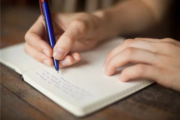 Personne écrivant un texte dans son carnet